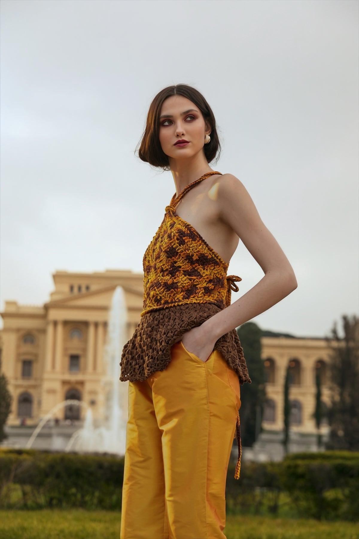 Blusa frente única feita à mão, em tons de amarelo, laranja e marrom, com peplum de renda marrom. Calça tafetá amarela. Tudo da marca Isabela Monteiro.