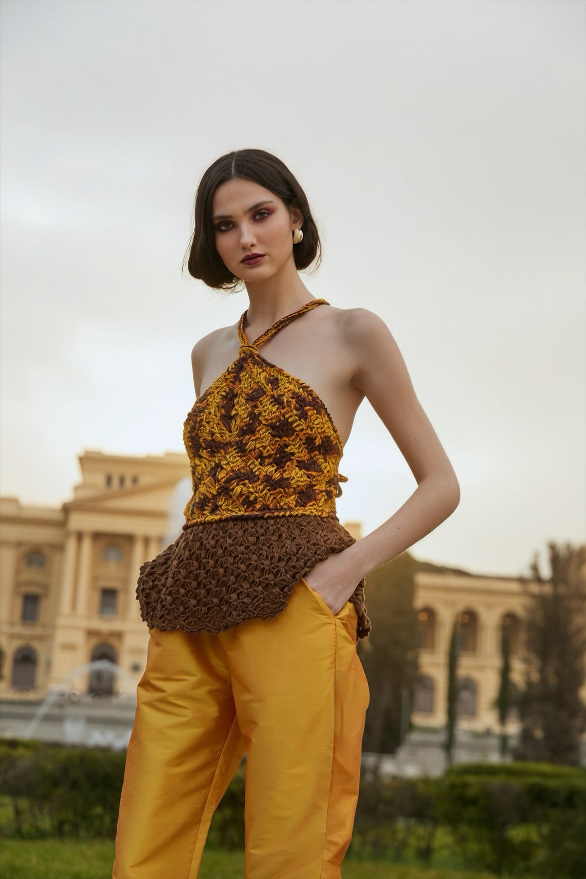 Blusa frente única feita à mão, em tons de amarelo, laranja e marrom, com peplum de renda marrom. Calça tafetá amarela. Tudo da marca Isabela Monteiro.