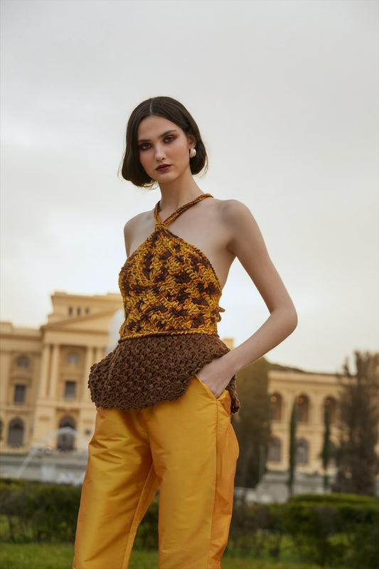 Blusa frente única feita à mão, em tons de amarelo, laranja e marrom, com peplum de renda marrom. Calça tafetá amarela. Tudo da marca Isabela Monteiro.