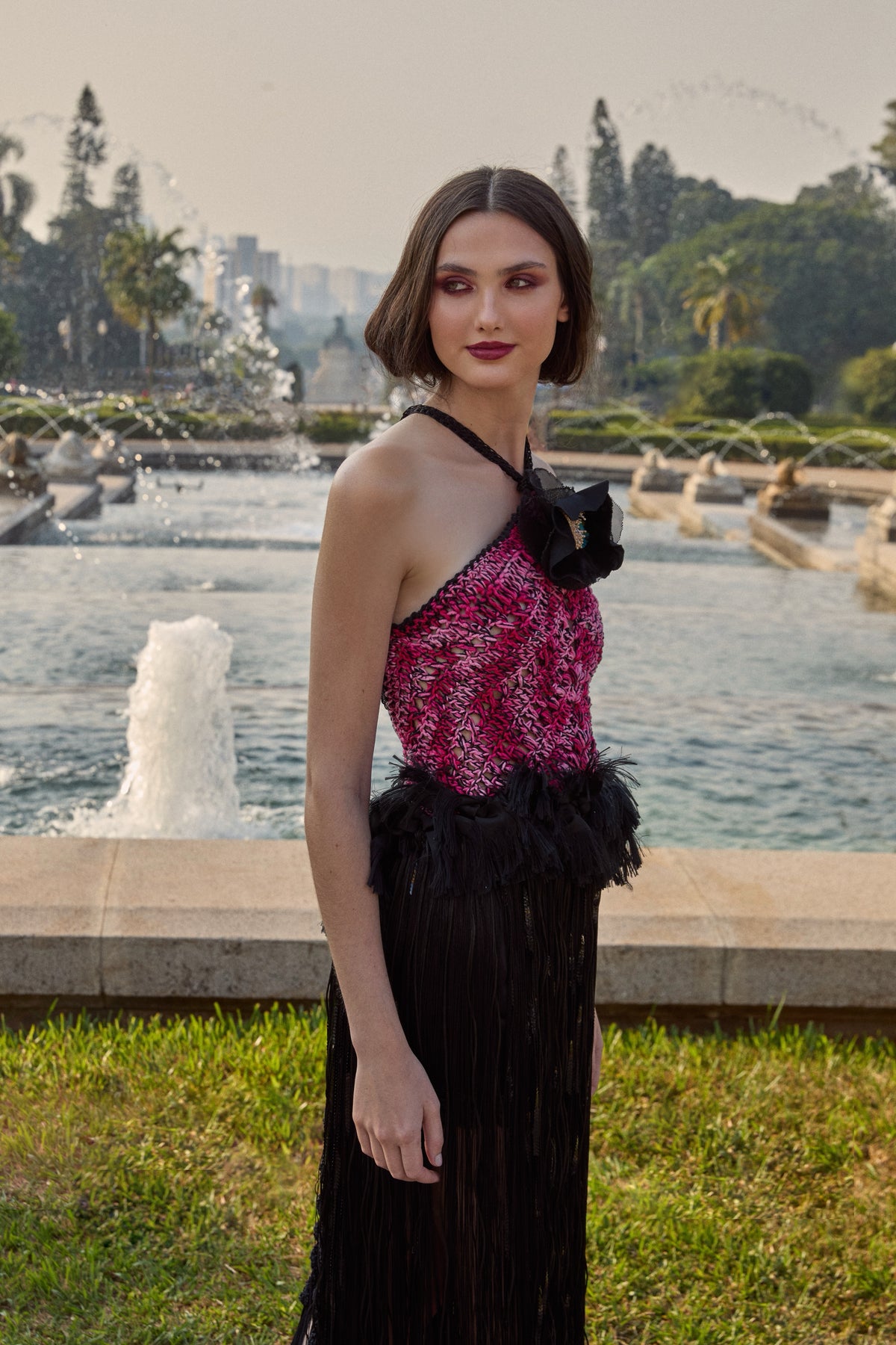 Frente única da marca Isabela Monteiro, feita à mão em crochê. Top rosa e preto que se prolonga em franjas pretas com toque de brilho de lantejoulas. Fitas desfiadas criam volume peplum tipo plumas. Flor de metal feita à mão com tafetá e pistilos decoram o decote na frente enquanto as costas ficam de fora.