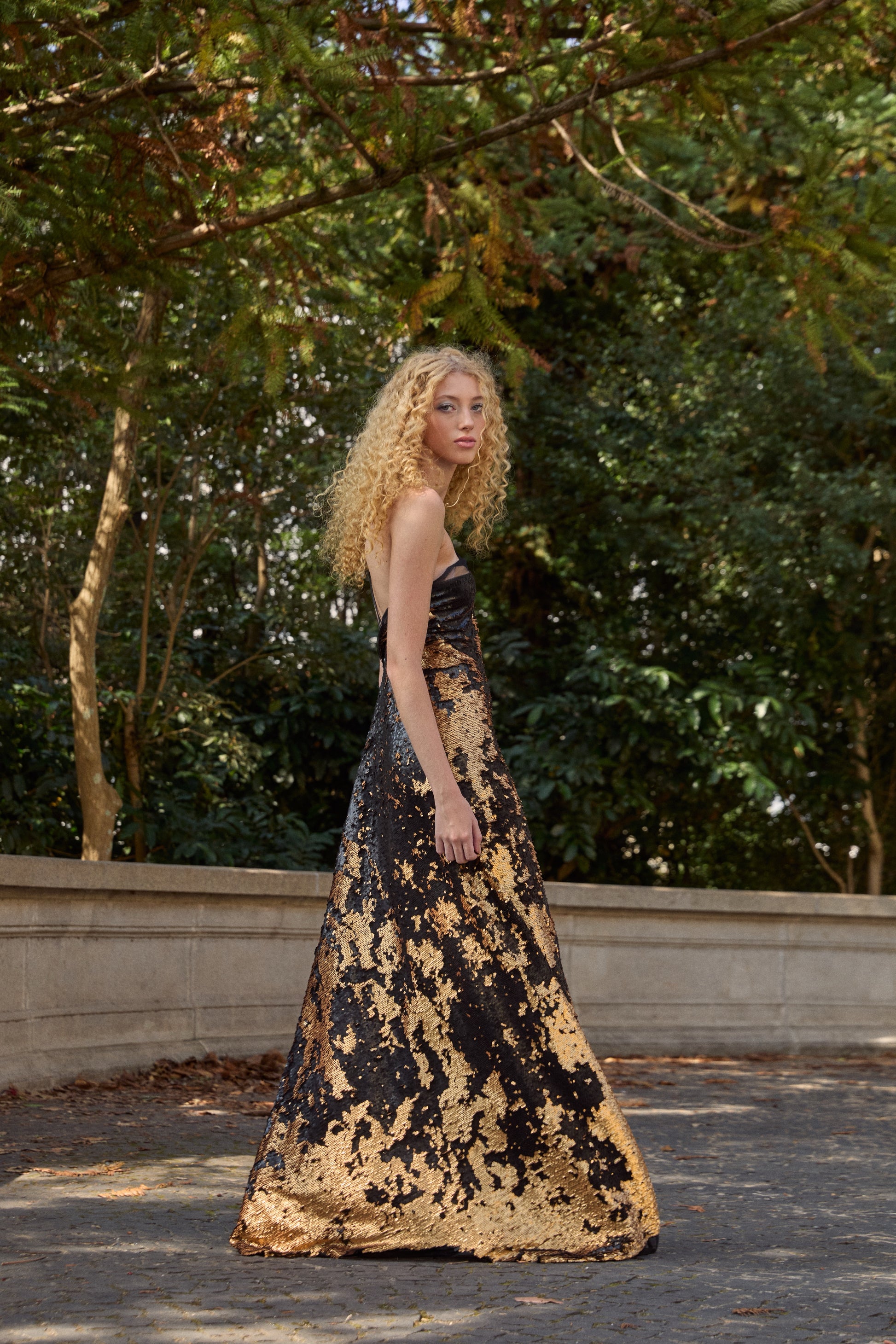 Vestido longo de festa da marca Isabela Monteiro, inteiro de paetê preto e dourado. O corte enviesado acompanha e desenha o corpo. Decote assimétrico na frente e profundo nas costas.