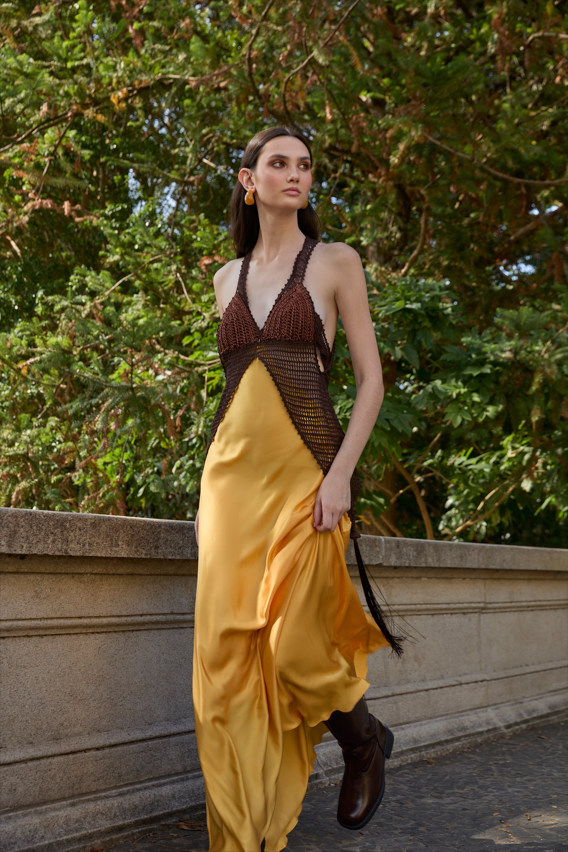Vestido longo de cetim de viscose amarelo e busto marrom inteiramente feito à mão em crochê, da marca Isabela Monteiro.