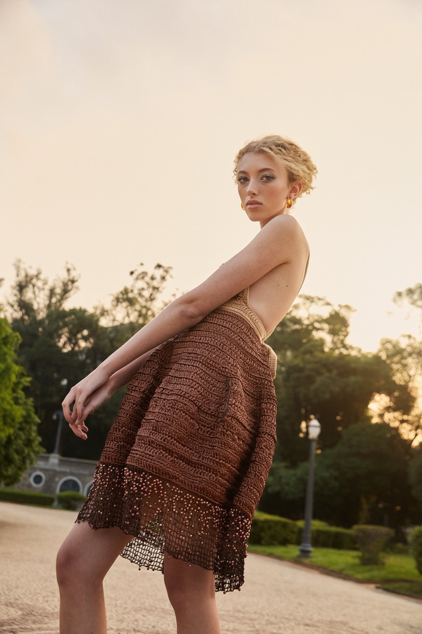 Vestido da marca Isabela Monteiro, todo feito à mão em crochê, em tons de marrom e castanho, com barrado em ponto filé e pedraria degradê para efeito bordado.